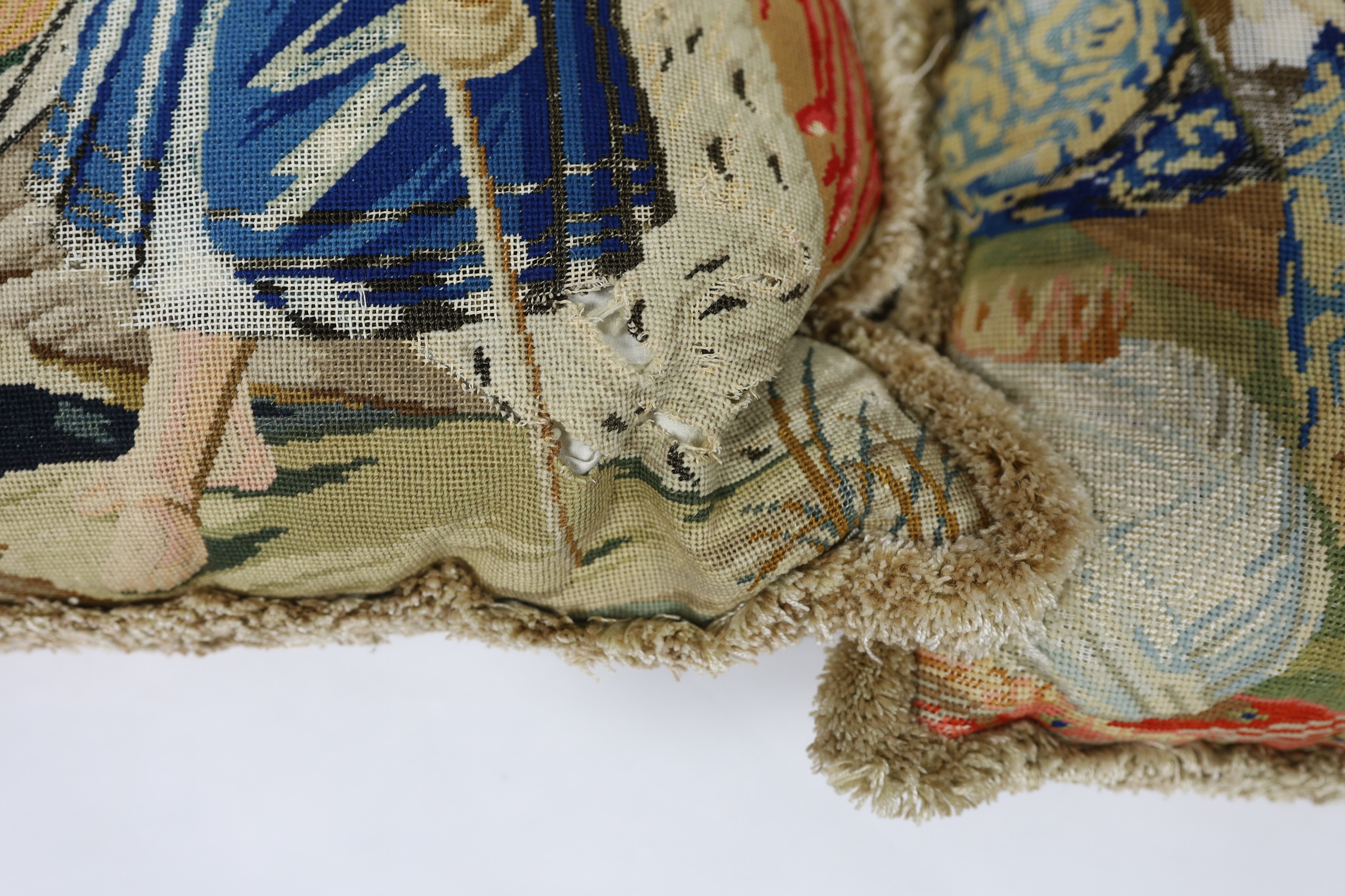 A very large Victorian Berlin wool worked cushion of possibly Queen Victoria's daughters on horseback being led by a gentleman in uniform, the cushion is edged with red tasselling, together with two similar Victorian Ber